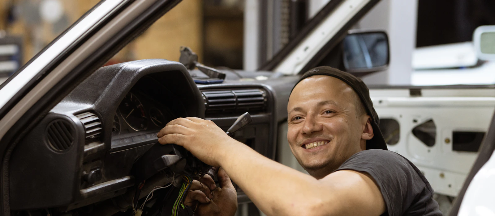Auto electrician at work under a car dashboard